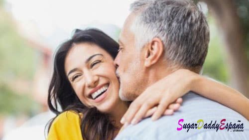 Hombre con canas dando beso a chica joven