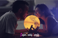 hombre y mujer en la cama sujetando un globo de la tierra que luce