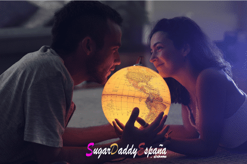 hombre y mujer en la cama sujetando un globo de la tierra que luce