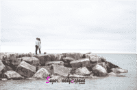 Chica y chicos de lejos abrazados en las rocas del mar